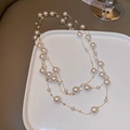 Elegante collana a strati con perle barocche e catena dorata su un piatto decorativo - Stile Catena Dorata Con Perle Multistrato Bianche