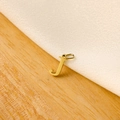Detailed view of a gold letter J pendant on light wood and white textile background - 14k Letter - J (letter Height 1cm)