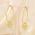 Detail of gold heart lock pendant on twisted rope earrings on a pink jewelry stand - Gold