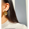 Pendiente de botón irregular dorado con textura martillada única mostrado en la modelo - Dorado