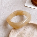 Detailed top view of a translucent amber resin bangle with marble texture on stone tray - 11# Bangle-Coffee-Square