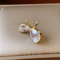 Dettaglio della spilla a fiocco dorata con zirconi a goccia su fondo champagne - Spilla a Fiocco in Zircone Dorato