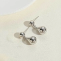 Detalle de pendientes de gota plateados con perla metálica minimalista y acabado liso - Doble Cuentas / Color Platino
