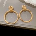 Detailopname van gouden metalen oorbellen met gedraaide knoop en dubbele ringen - Knoop Ring Stijl / Goud