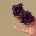 Detail of elegant purple fabric rose stud earrings with dewdrop beads on a hand - Purple