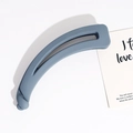 Detail of matte grey-blue banana hair clip featuring a modern twisted knot structure - Gray