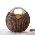 Fashionable brown round woven straw handbag with cream handles on a rustic wooden table - Dark Brown