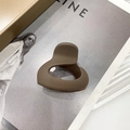 Minimalistische matte Haarklammer in Kaffeebraun, Herzform auf Zeitschriftenhintergrund - Braun