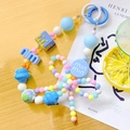 Close-up of colorful beaded phone strap with candy-colored resin beads on wooden desk - M Round Tag / Blue