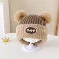 Dettaglio cappello in maglia per neonato con etichetta CAP e due morbidi pompon in pelliccia - 2-5 Anni / Lettere CAP / Marrone