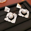 Dettaglio macro di orecchini geometrici in argento con grandi perle e strass brillanti - Argento