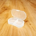 Translucent two-compartment pill cutter box with flip-top lid on wood table - Mini 2-Grid Transparent Pill Box