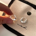 Close-up of silver U-shaped geometric twist earrings displayed on a canvas pouch - Twisted Wave Hoop / Silver