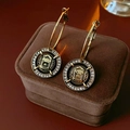 Gold hoop earrings with black circular pendants and crystal inlay on a velvet box - Steel Earring Post / Black Relief Round Hoop Earrings