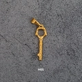Vintage golden key pendant with hexagonal head and textured stem on a grey stone surface - H05-Irregular Hammered Key