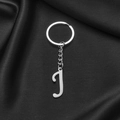 Polished stainless steel keychain with letter J pendant on elegant black silk background - Letter J