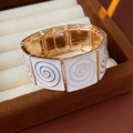 Macro shot of vintage gold squares with white enamel and spiral texture detail - Bracelet - Beige