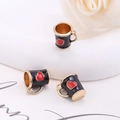 Vista macro de colgantes de taza de café negros con corazones rojos y bordes dorados DIY - Negro