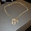 Macro shot of gold double pendant necklace with zircon-encrusted cross and vintage charm - Gold Cross Necklace