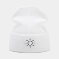 Close-up of sun embroidery detail on white cuffed knit beanie with soft texture - White