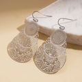 Detail of drop-shaped metal earrings with intricate hollow floral patterns on marble stone - Silver