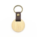 Detailed view of a round walnut wood keychain with dark brown leather strap and brass ring - Round Bamboo