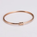 Dettaglio di un bracciale rigido in oro rosa con tre cursori zigrinati e fibbia a scatto - Oro rosa
