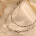 Primer plano de collar de tres capas en acero dorado 18K con pequeñas perlas blancas - Plateado