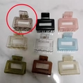 Set mit 9 farbenfrohen geometrischen Haarklammern in Gelee-Farben auf weißem Marmor - Braun