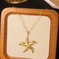 Macro shot of a golden starfish pendant necklace with fine texture on a wooden display - Gold Starfish Pendant Necklace