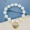 Bracciale di perle esotiche con ciondolo occhio del male dorato e mano di Fatima - Tondo Trasparente