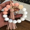 Close-up of pink silicone bead wristlet keychain with leather tassel and wood bead - Nude