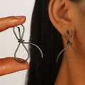 Detail eines minimalistischen dunkelgrauen Knoten-Ohrrings am Modellohr für die Größe - Drahtumwickelte Ohrringe mit Schleife (DZ-435-25) / Gunmetal