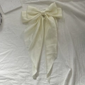 Elegant off-white satin bow hair clip with long ribbons on white textured fabric - Beige