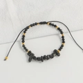 Detalle de una pulsera tejida a mano con piedras negras, cuentas y cordón ajustable - Negro