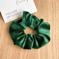 Close-up of deep green velvet scrunchie with ribbed texture on a wooden table - Green Velvet Scrunchie