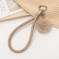Détail du porte-clés dragonne tressée beige chameau avec pompon doux et anneau en métal - Marron
