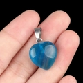 Pendentif cœur en cristal bleu 16mm avec fermoir argenté présenté sur le bout du doigt - Agate bleue