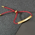 Close-up of red braided rope bracelet with polished gold-plated metal bar and adjustable slider - Red Rope Gold