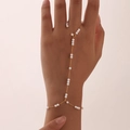 Detailed view of elegant gold-plated hand harness with white pearls on a model's hand - Pearl Decor / Gold
