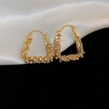 Macro shot of U-shaped gold plated earrings featuring micro-paved zircons on silk fabric - U-Shaped Ear Buckle / Gold