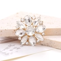 Macro shot of marquise crystal flower accessory with gold base on a beige stone - White