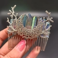 Silver metal hair comb with rainbow crystal points and branch details in hand view - Grey + Branch + Moon