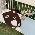 Nahaufnahme einer braunen Häkeltasche mit weißen Blumenmustern auf einer weißen Bank - Dunkelbraun