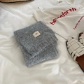 Detail shot of folded grey wool blend scarf with a small label on a white bed sheet - 3g Series / Light Gray