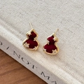 Golden gourd earrings with red velvet and zircon stars on a linen book background - Red