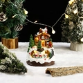 Makroaufnahme der beleuchteten Lebkuchenhaus-Weihnachtsdeko mit warmen LED-Lichtern und Schnee - Einzelnes Dach Lebkuchenmann