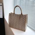 Striped jute tote bag with brown chevron pattern and dual handles in a bright setting - Brown
