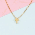 Nahaufnahme einer minimalistischen goldenen Edelstahl-Kreuzkette auf einem sanften Pastellhintergrund - Gold