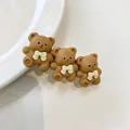Nahaufnahme von drei matten braunen Bären-Haarspangen mit weißen Schleifen - Bär Kaffeefarbe